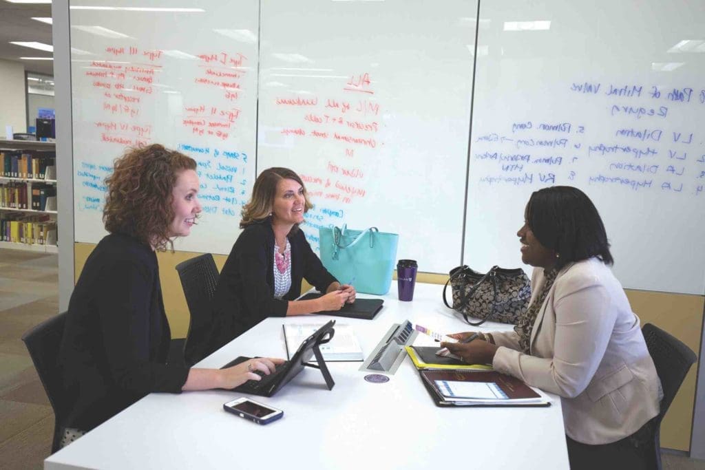 Group of three adult students studying at a table in the Learning Commons