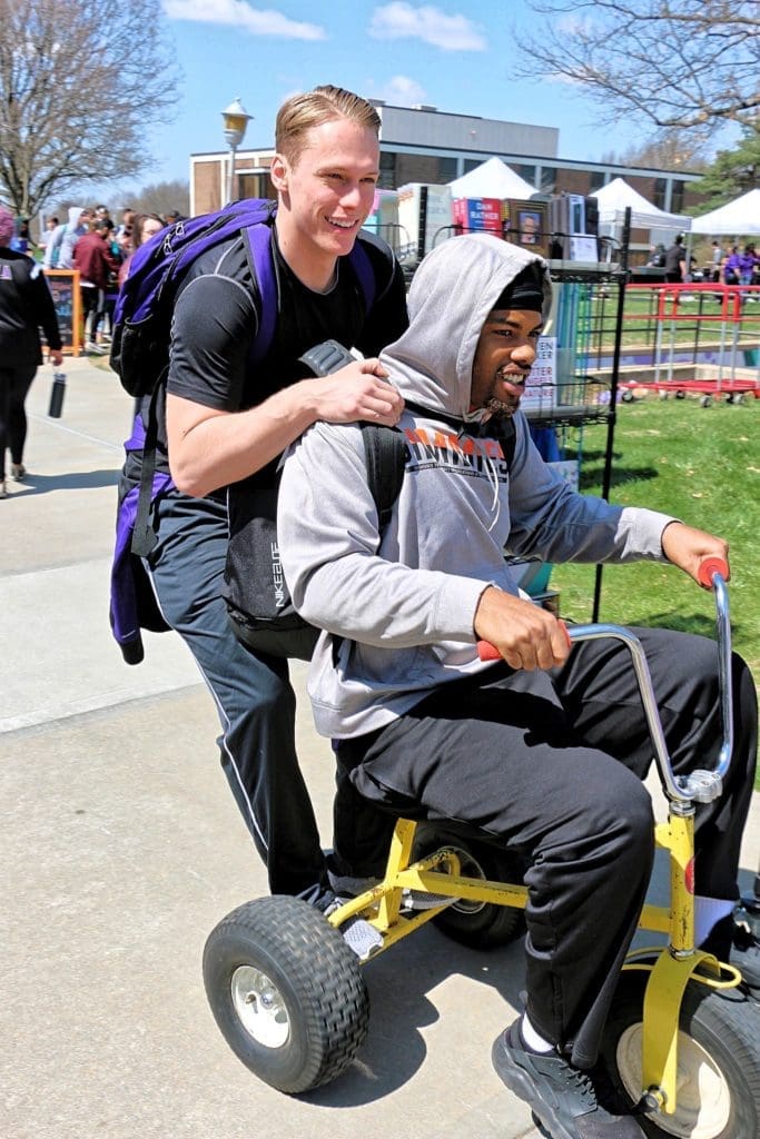 Two students riding a giant tricycle during the campus carnival