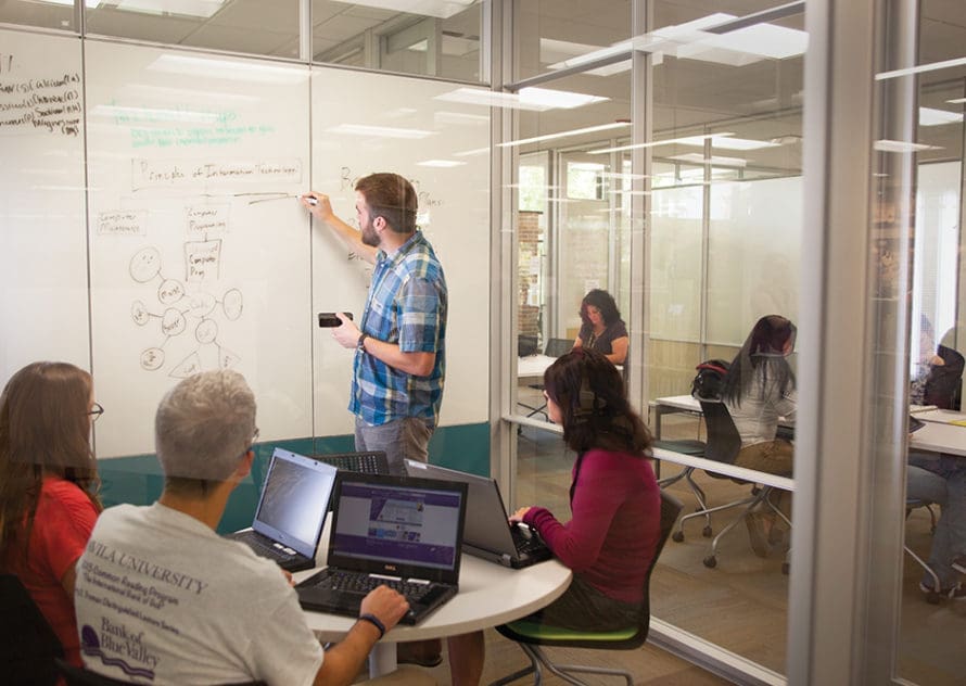 Adult students inside the Learning Commons with a whiteboard behind