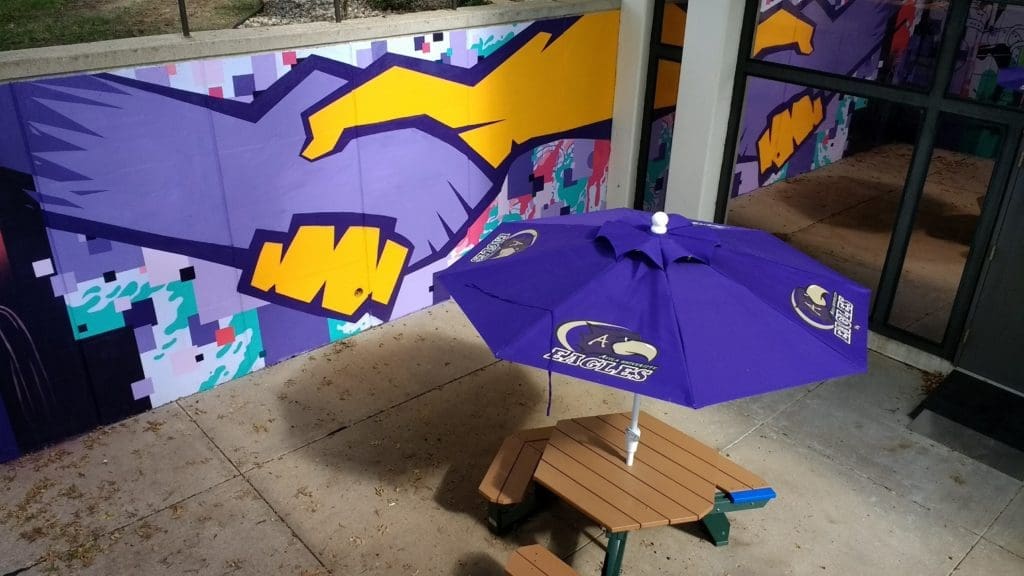 A portion of the mural depicting a handshake and a picnic table inside the moat surrounding Marian Center