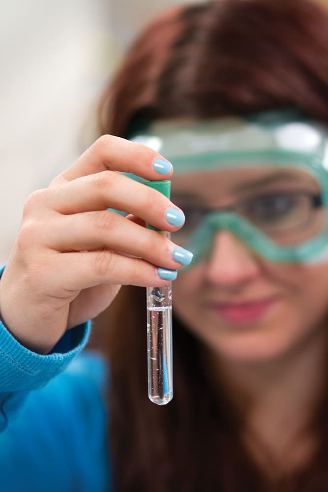 Close up of a student holding a test tube holding a clear liquid